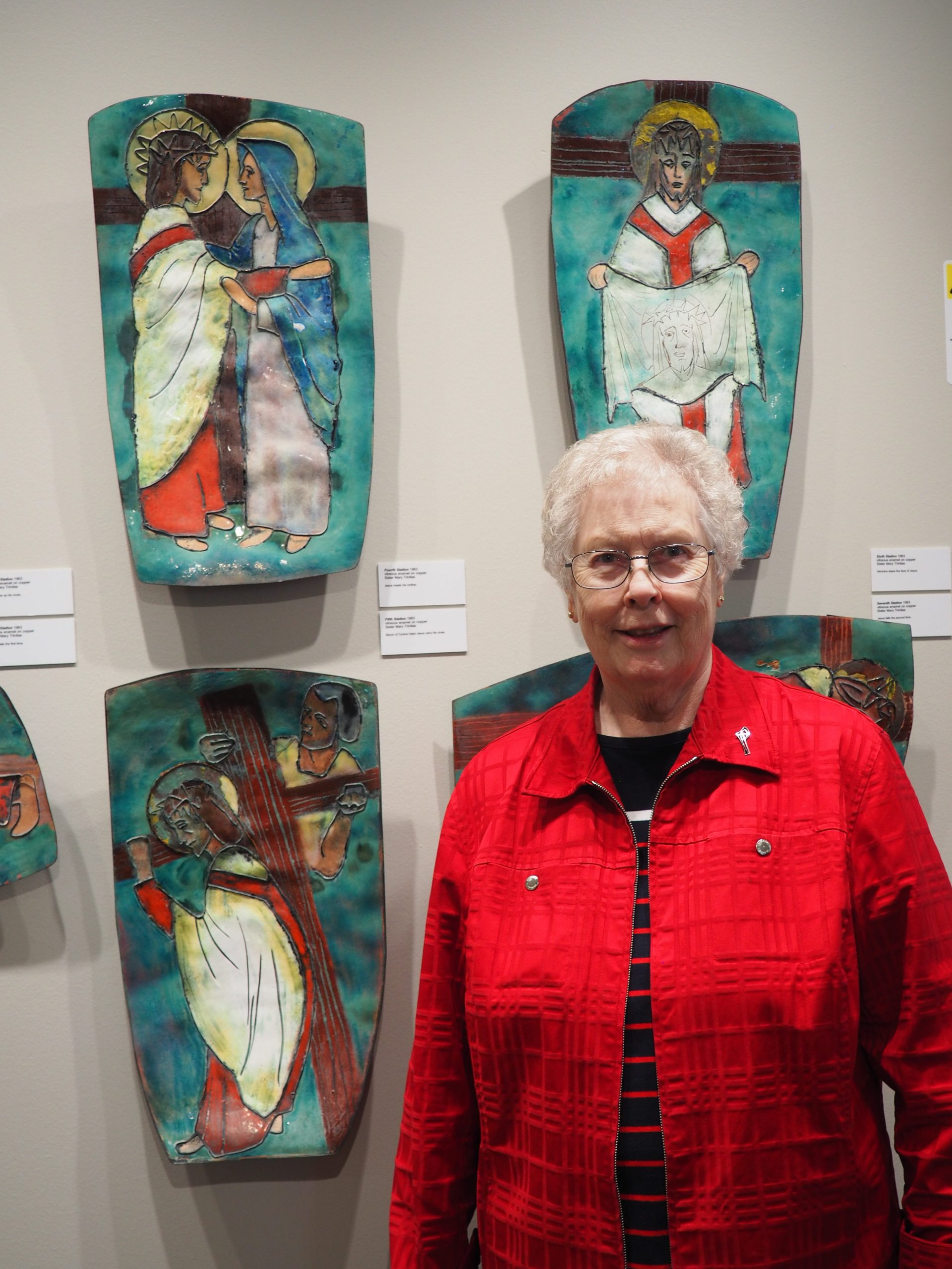 Sister Mary Hawkins stands in front of stations of the cross artwork on a wall