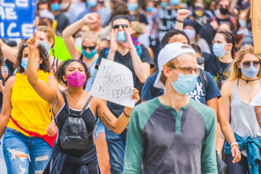 demonstrators wearing masks and carrying signs