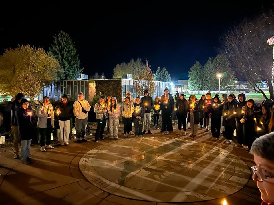 Des étudiants, des professeurs et des membres du personnel de l'université de Providence tiennent des bougies pendant un moment de silence lors d'une veillée en l'honneur des victimes de la violence domestique.