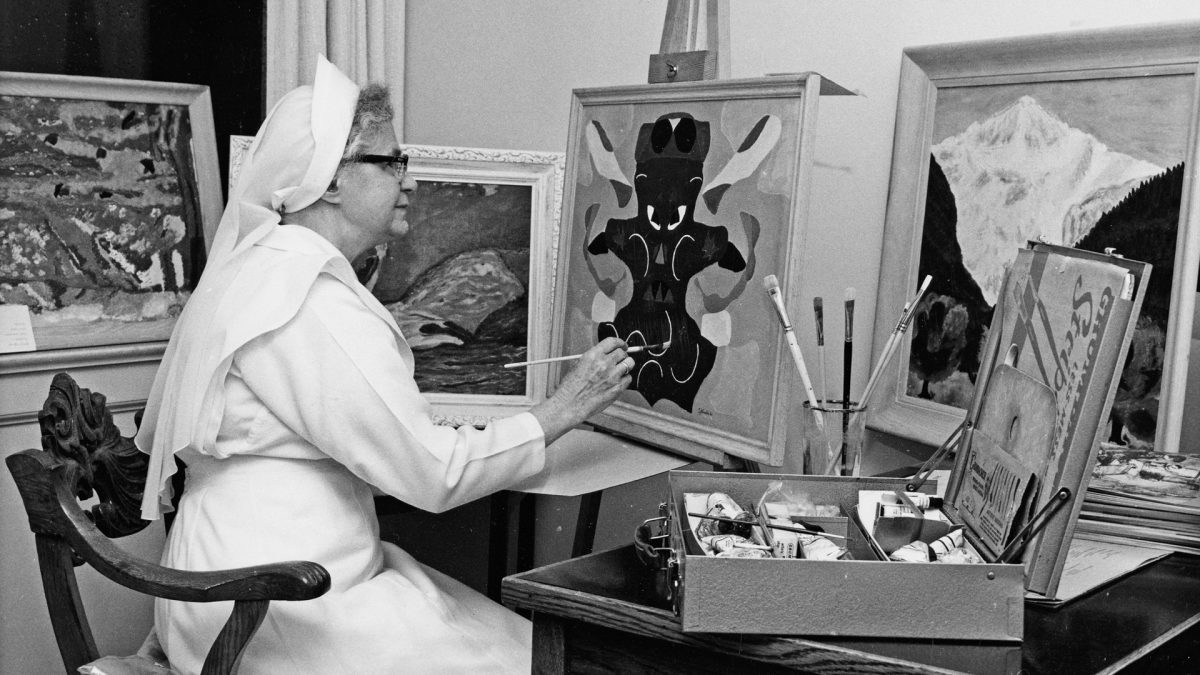 A religious Sister paints in a studio.