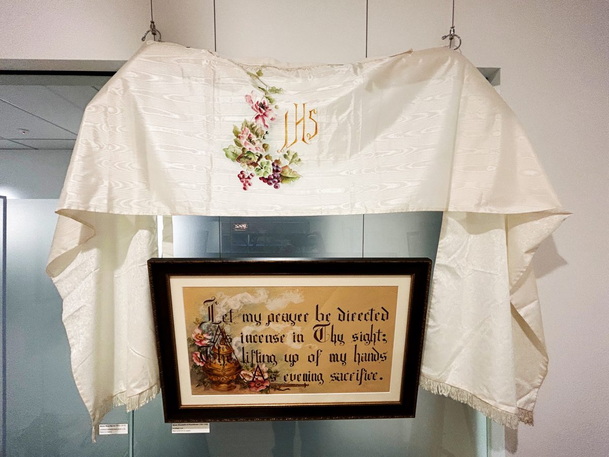 A painted stole and a calligraphy painting inside an art exhibit.
