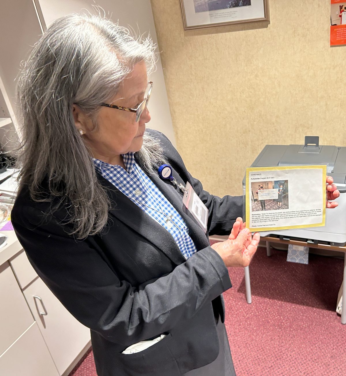 Sr. Fe Sumalde displays a printed recognition in her hands.