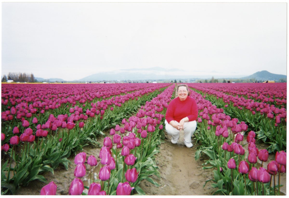An archival photo of Sr. Patricia Glen posing in a field of tulips.