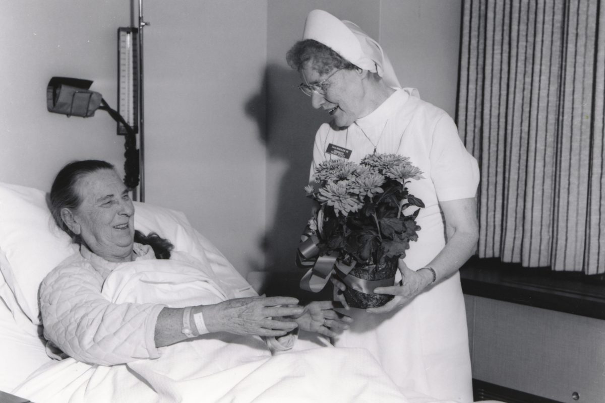Sr. Magdalene of Providence delivering flowers to a patient, Sacred Heart Hospital, Spokane, Washington, ca. 1968